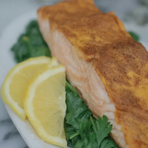 Perfectly pan-seared keto salmon fillet with lemon and dill garnish.